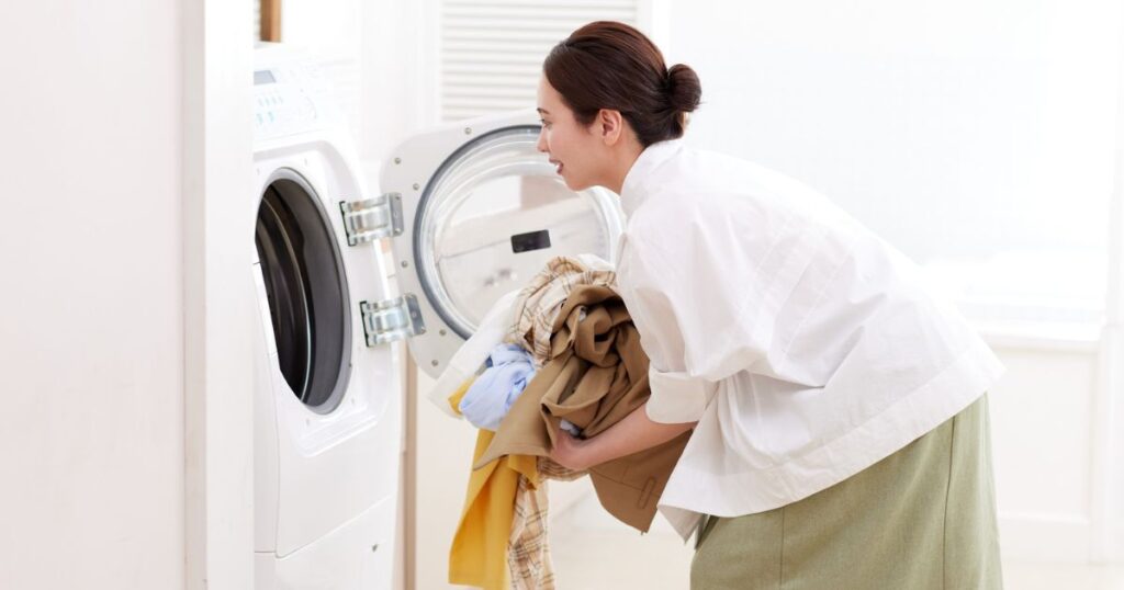 ドラム式洗濯機に洗濯物を入れる女性